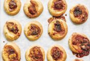 Fig jam thumbprint cookies in rows on a sheet of parchment paper.