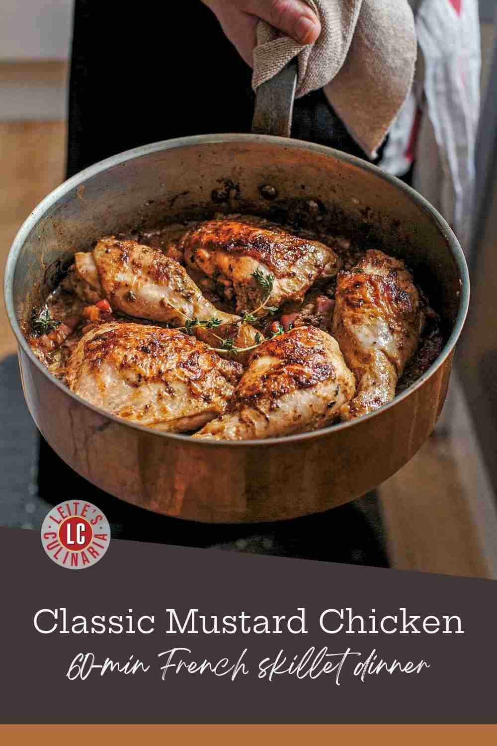 Golden-brown chicken thighs and drumsticks in a copper skillet with a creamy mustard sauce and fresh thyme.