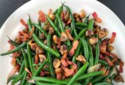 Green beans with bacon and shallots in a large white dish.