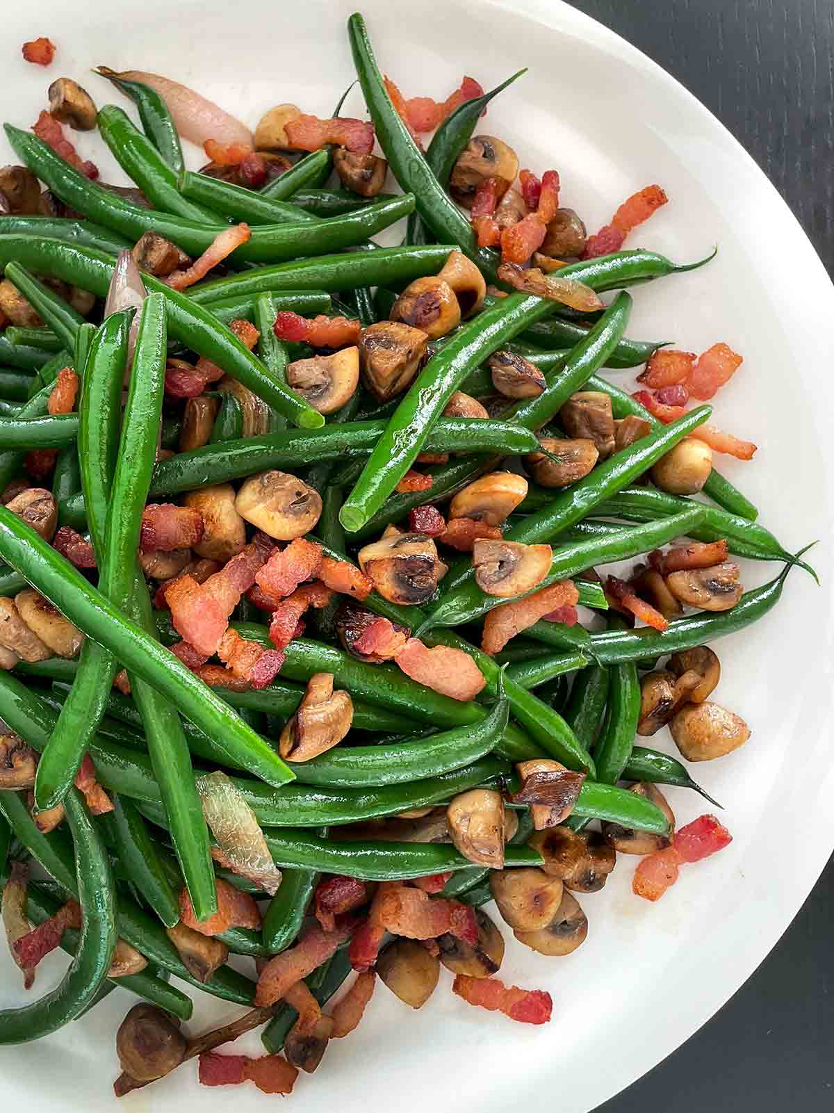 Green beans with bacon and shallots in a large white dish.
