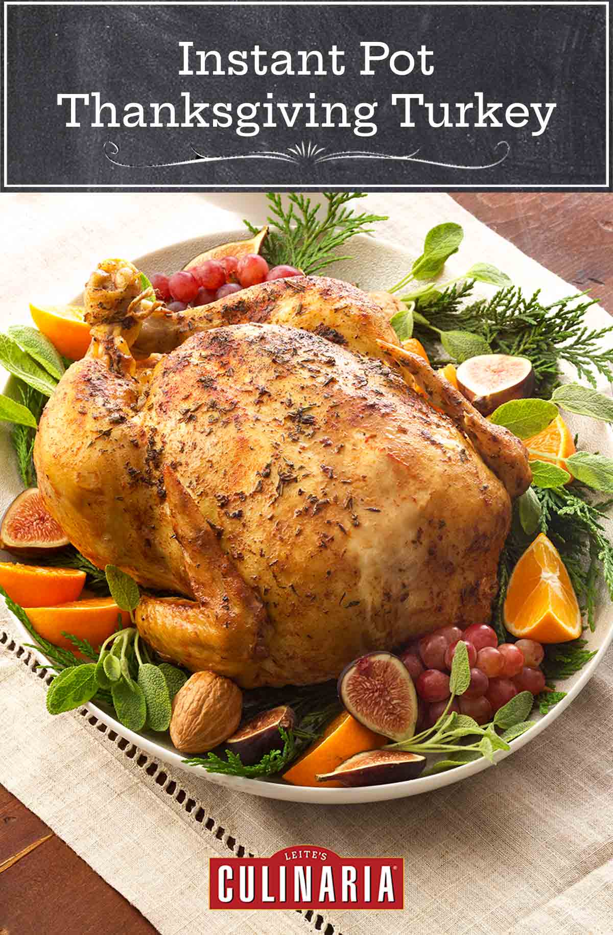 Instant Pot Thanksgiving turkey on a platter garnished with figs, oranges, grapes, and sage, beside a carving set.
