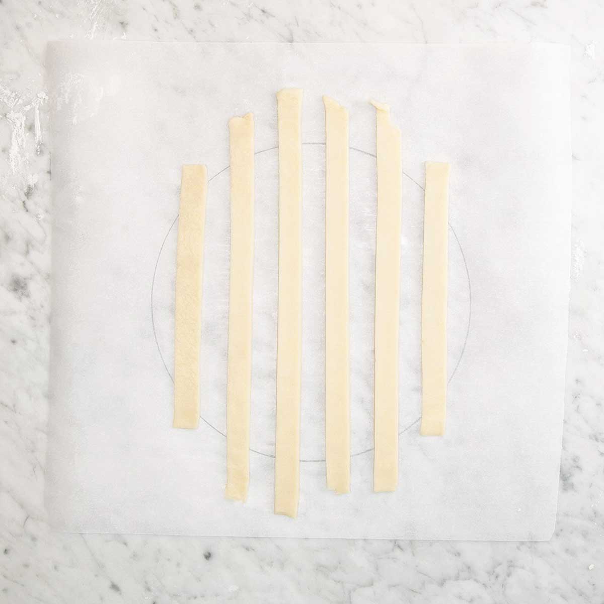 Six strips of dough arranged side by side for a lattice pie crust.