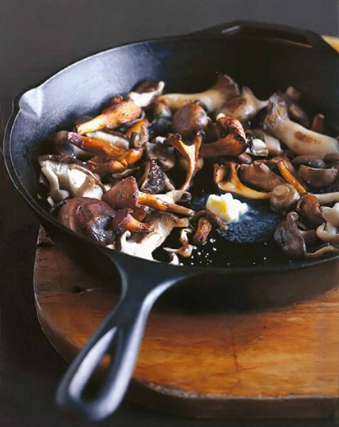 Pan-roasted mushrooms and a knob of butter melting in the center, in a cast-iron skillet