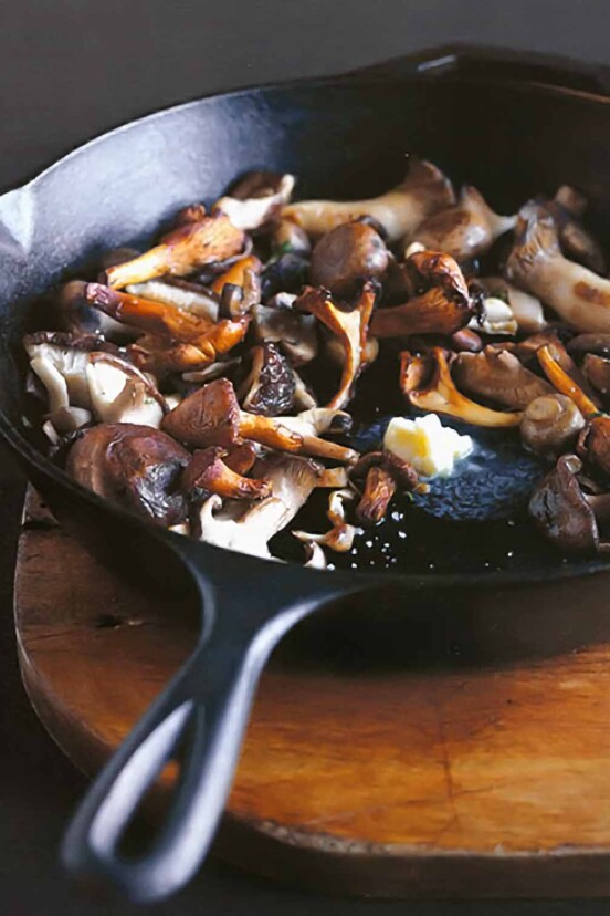 Pan-roasted mushrooms and a knob of butter melting in the center, in a cast-iron skillet
