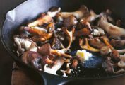 Pan-roasted mushrooms and a knob of butter melting in the center, in a cast-iron skillet.