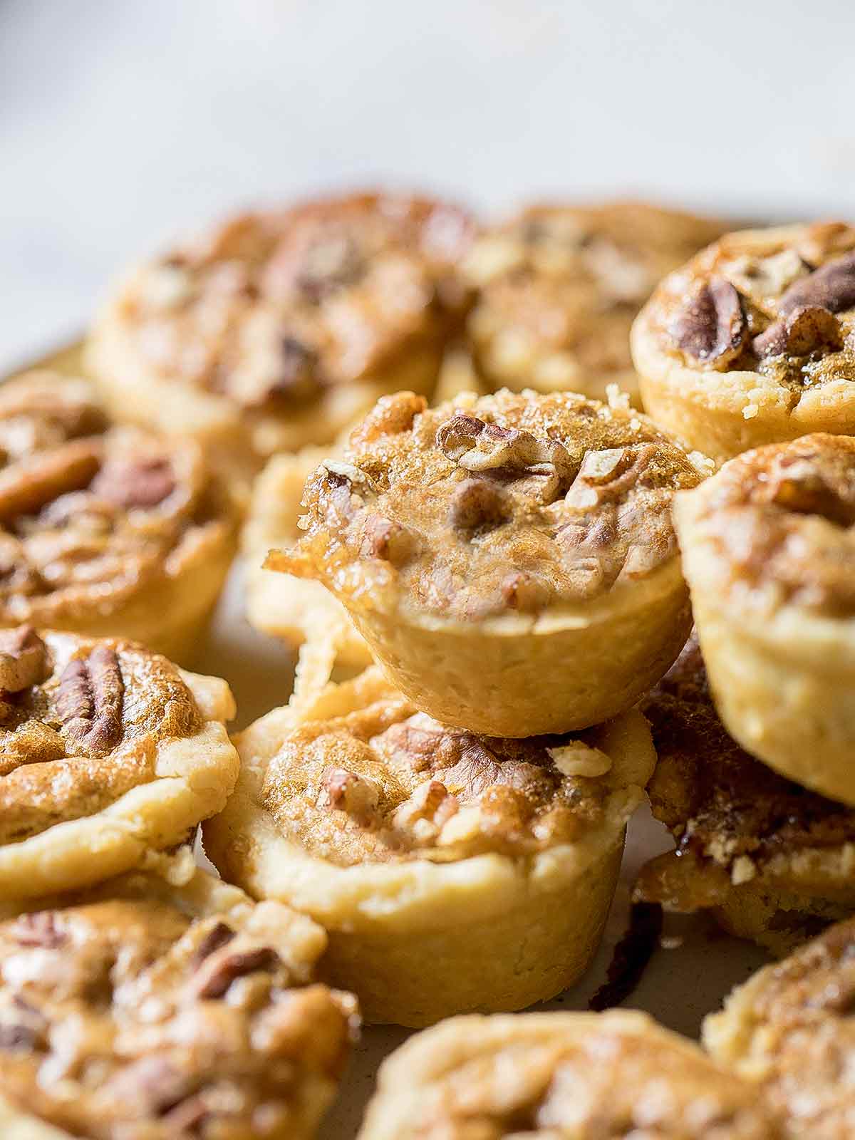 Pecan tassies in close-up, piled on top of each other.
