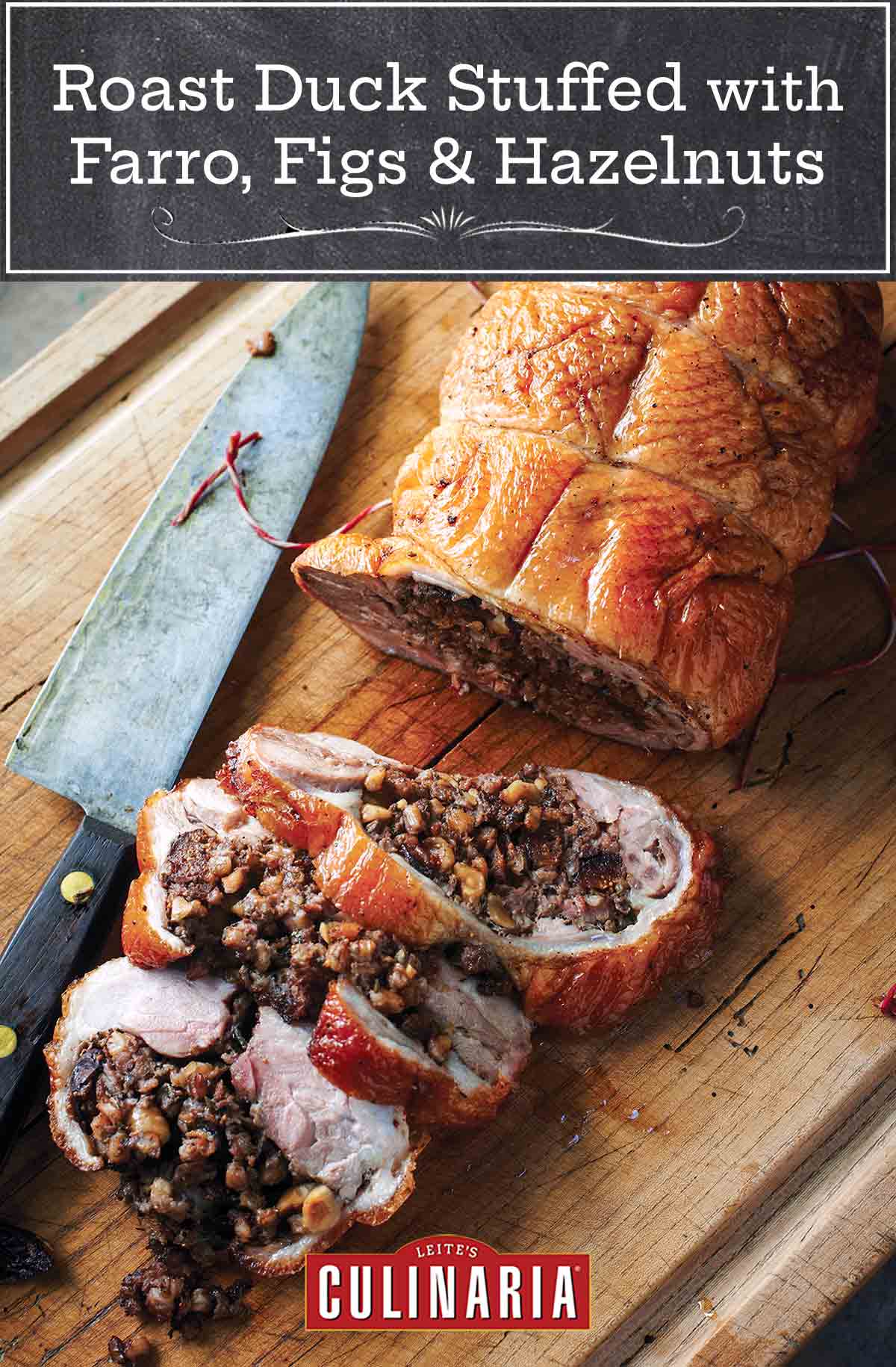 A roast duck stuffed with farro, figs, and hazelnuts, with three slices cut from it on a wooden cutting board with a knife resting beside it.