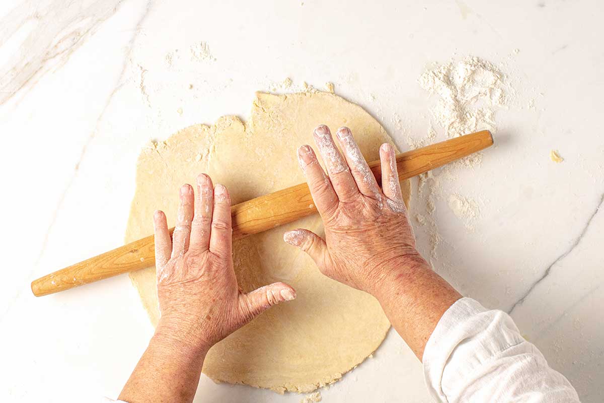 A person rolling out a pie crust.