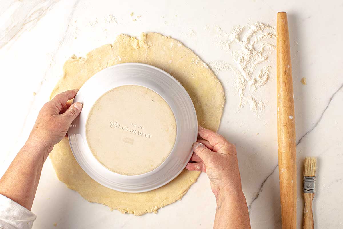 A pie plate being placed over a rolled out pie crust.