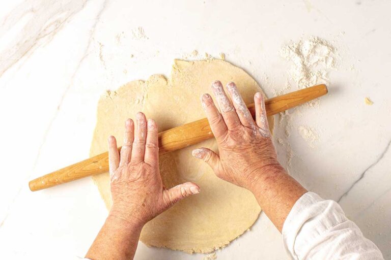 A person rolling out a pie crust.