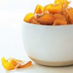 Sea salt-rosemary sweet potato chips piled in a white bowl, with a few laying beside it.