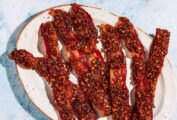 Seven strips of air fryer pecan praline candied bacon in a white plate