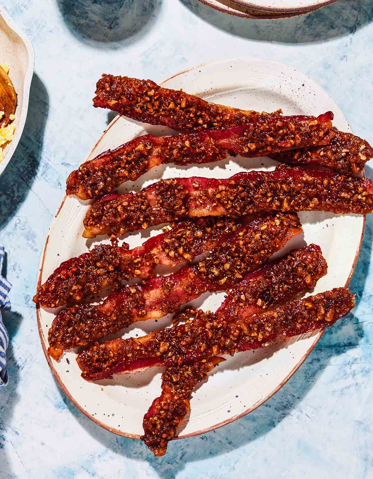 Seven strips of air-fryer pecan-praline candied bacon in a white plate