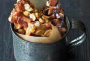 Bacon peanut brittle in shards, in a mug lined with parchment paper.