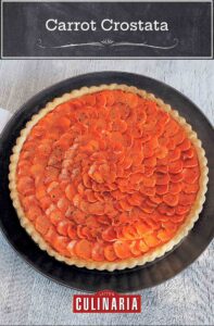 Carrot crostata on a large black plate, with a white napkin on a wood table.