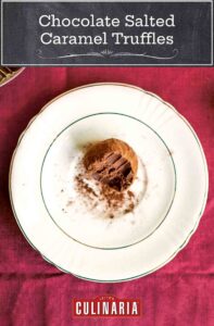 A chocolate salted caramel truffle with a bite taken out of it, on a white saucer, on a red tablecloth.