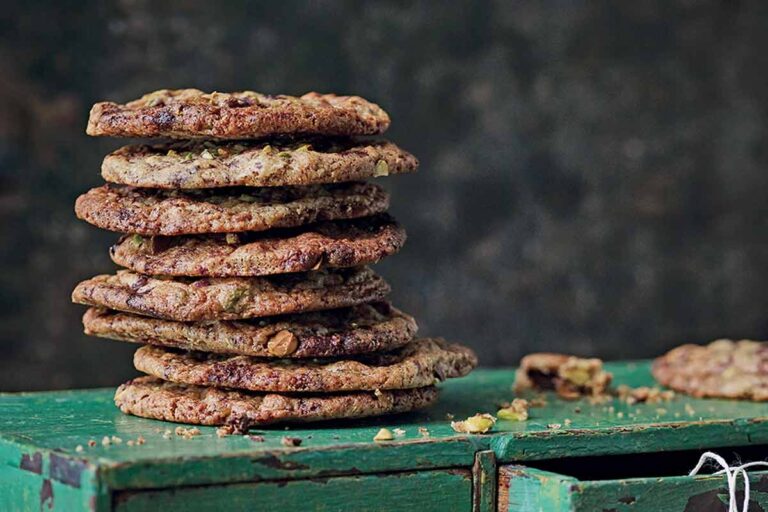 Clove cinnamon and chocolate cookies stacked up on a green cupboard with twine.