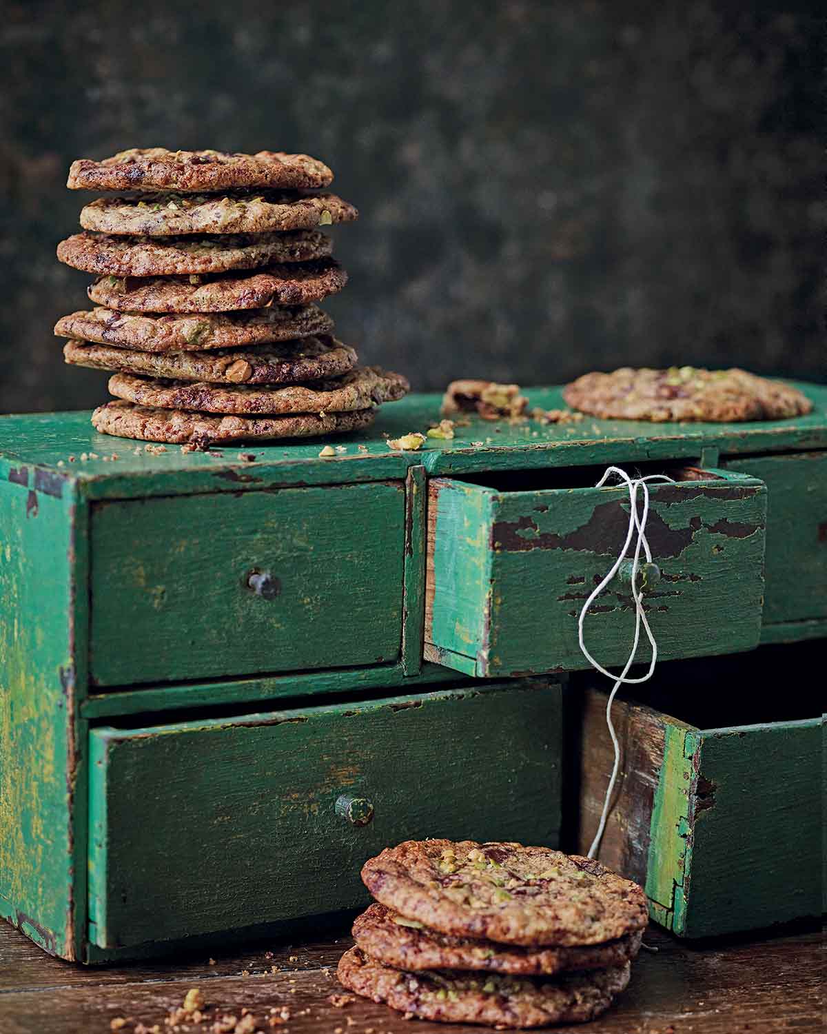 Clove cinnamon and chocolate cookies stacked up on a green cupboard with twine and another stack of cookies in front.