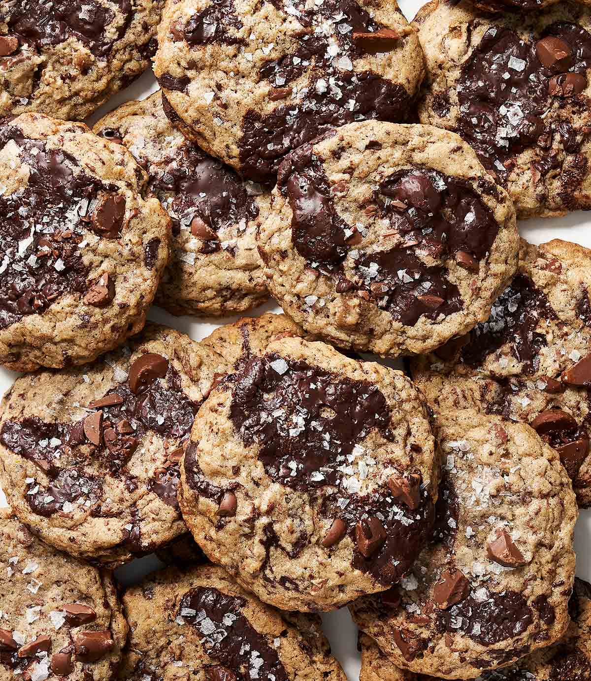 Double chocolate chunk cookies garnished with flaky salt, piled on a piece of parchment.