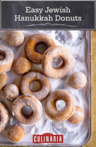 Easy Jewish Hanukkah doughnuts and doughnut holes covered with sugar, on a metal cookie sheet.