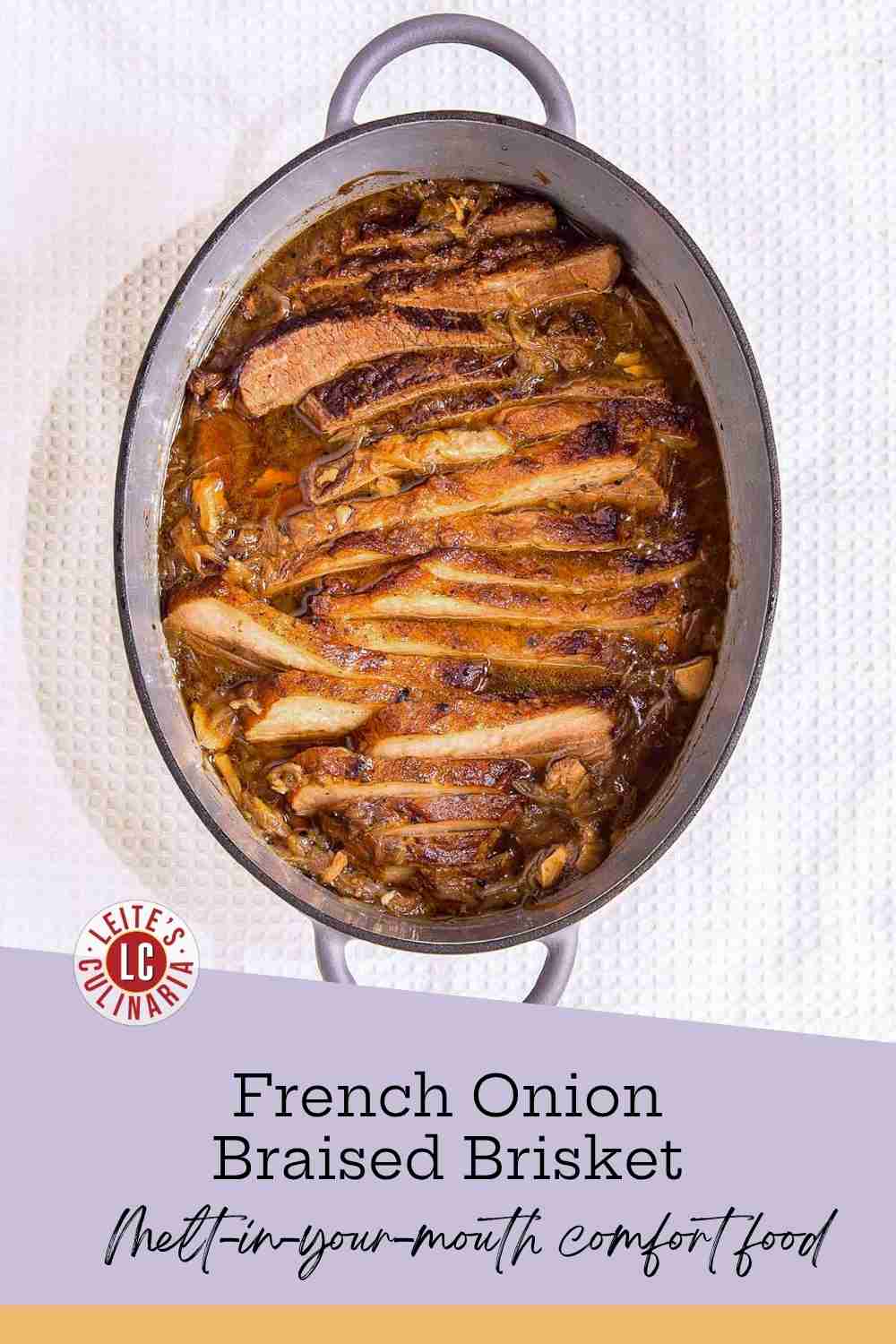 Sliced beef brisket nestled in caramelized onions and dark savory gravy inside a grey oval Dutch oven.