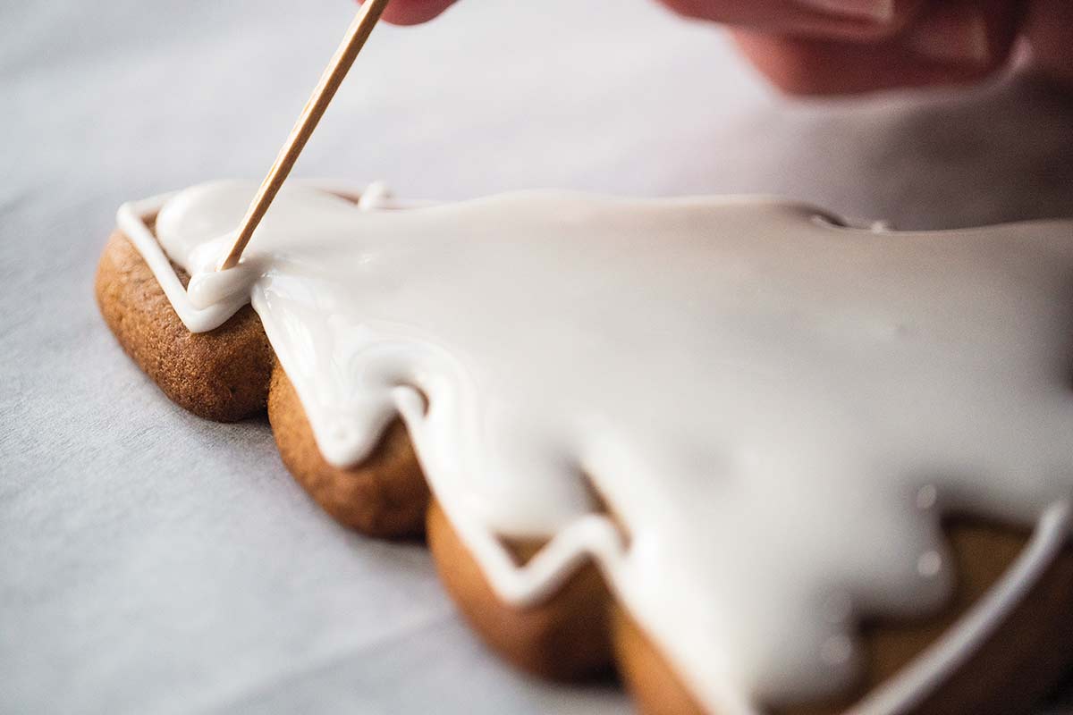 A tree-shaped cookie being filled with royal icing.