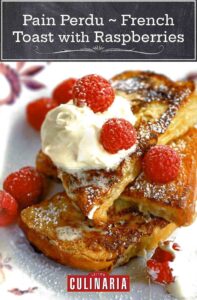 Pain perdu-French toast with raspberries piled on a plate dusted with icing sugar, a dollop of whipping cream, and raspberries.