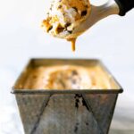 A container of Pumpkin Meringue Pie Ice Cream with a scoop.