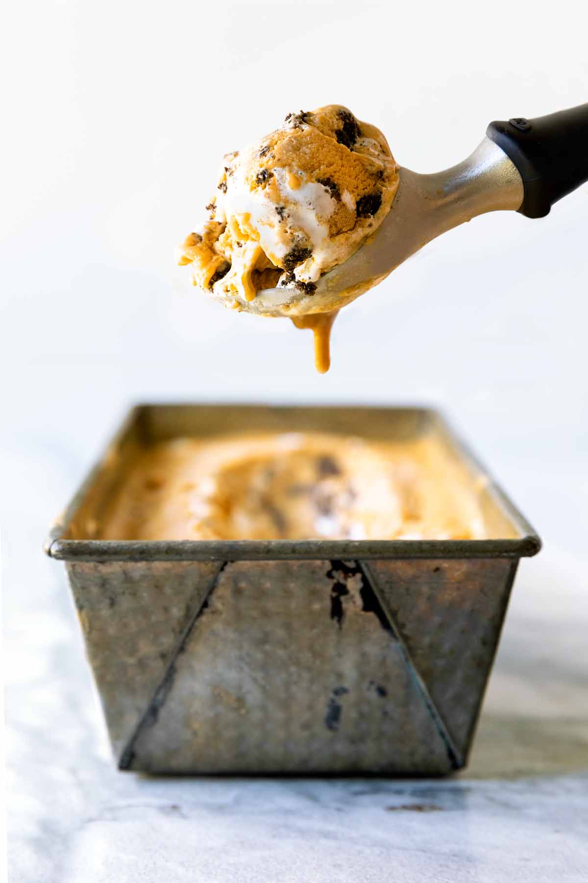 A container of Pumpkin Meringue Pie Ice Cream with a scoop.