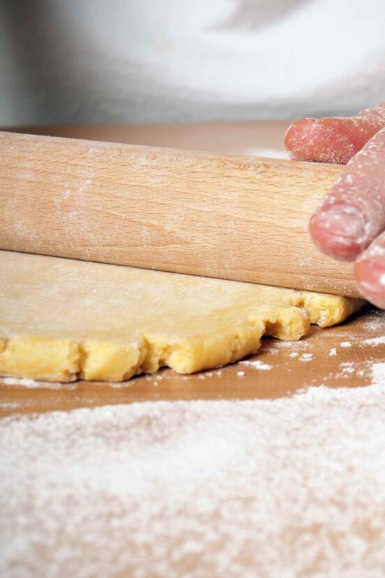 Hands rolling out pie dough.