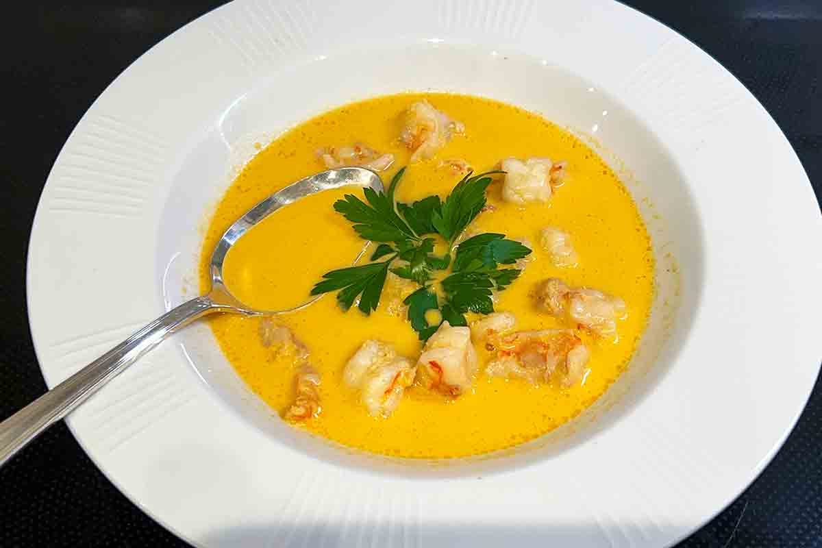 Two bowls of shrimp bisque on a black table