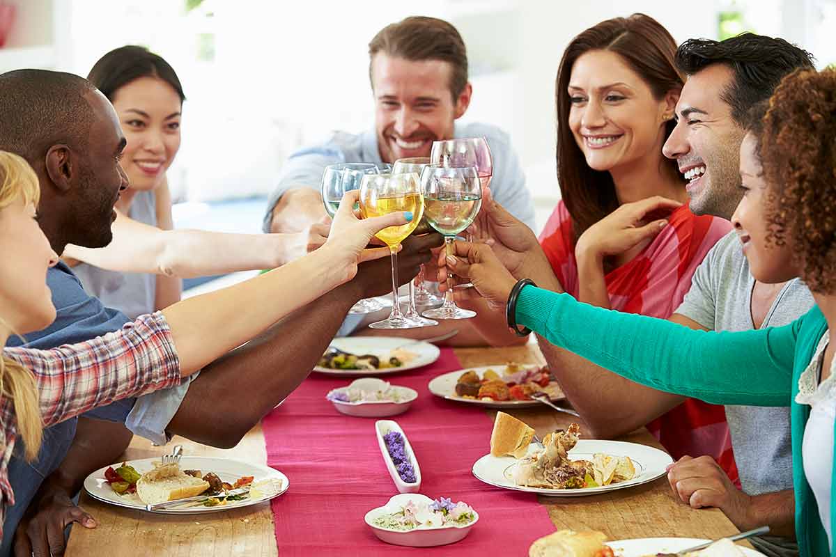 A group of friends sitting at a table toasting wine glasses.