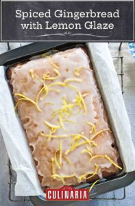 Spiced gingerbread with lemon glaze garnished with lemon zest strips, in a parchment-lined cake pan.