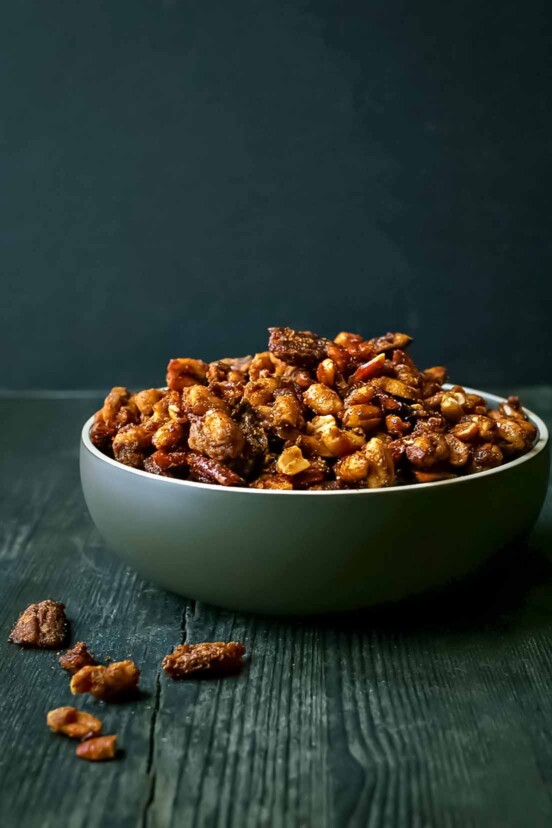 Sweet and spicy roasted nuts in a large green bowl on a wooden table.