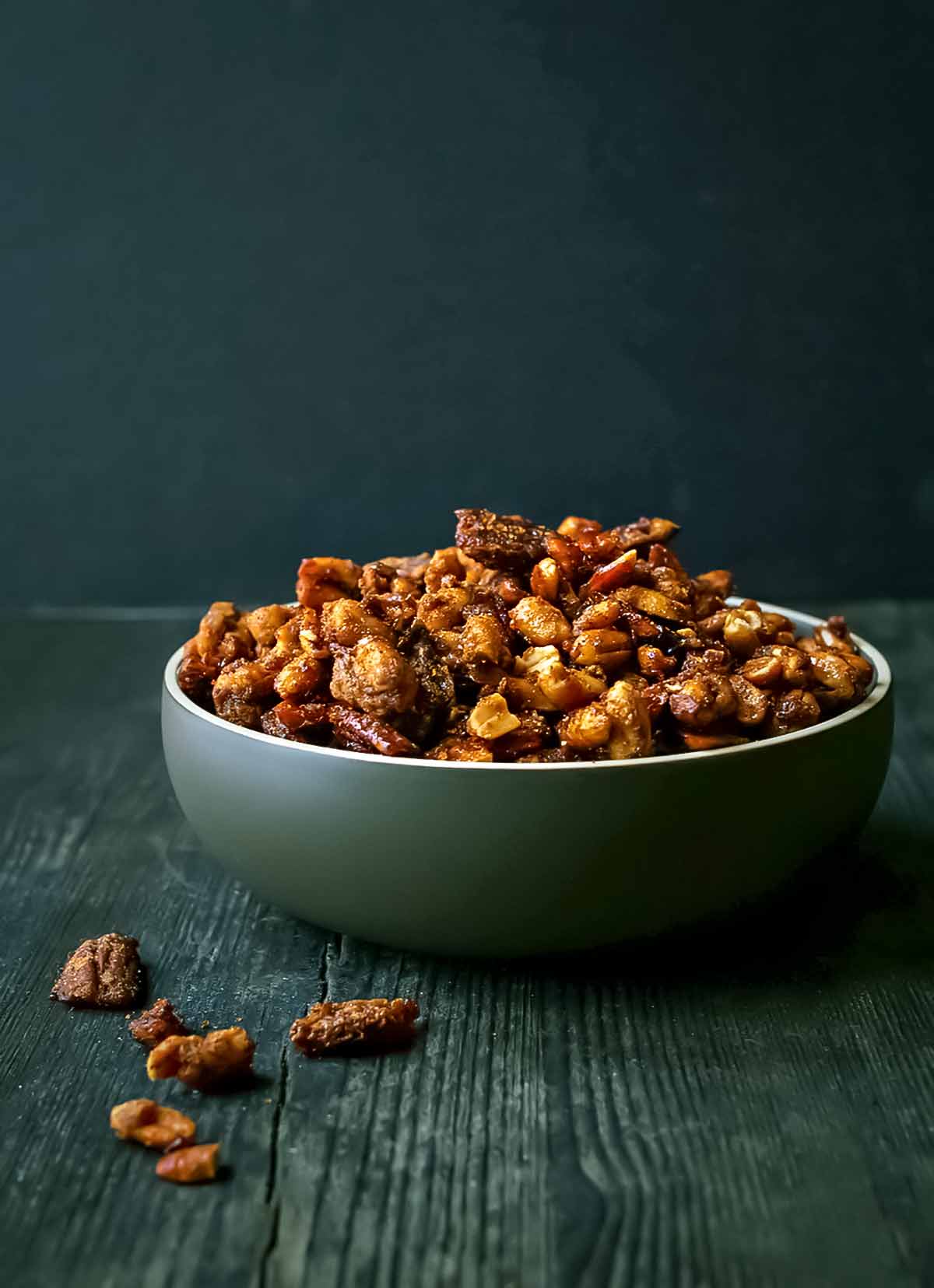 Söta och kryddiga rostade nötter i en stor grön skål på ett träbord.