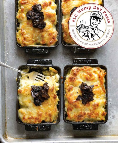 Truffled mac and cheese in four mini-casserole pans, one with a fork and a few mouthfuls missing.