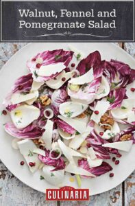 Walnut fennel and pomegranate salad garnished with walnuts and pomegranate seeds, on a white plate.