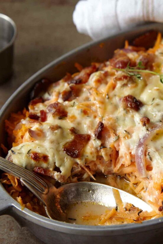 A chicken, sweet potato, and bacon casserole in an oval dish, topped with melted cheese