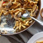 A white plate of Everything But the Kitchen Sink Pasta on a white crackly tabletop