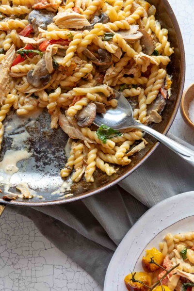 A white plate of Everything But the Kitchen Sink Pasta on a white crackly tabletop