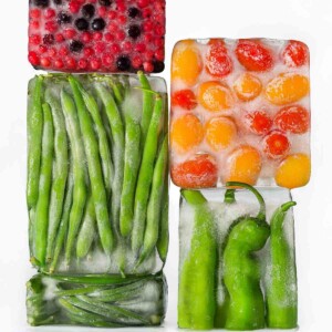 Our guide to freezing vegetables properly--four blocks of ice with berries, cherry tomatoes, green beans, and fava beans frozen inside