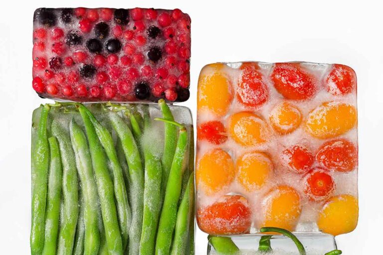Our guide to freezing vegetables properly--four blocks of ice with berries, cherry tomatoes, green beans, and fava beans frozen inside