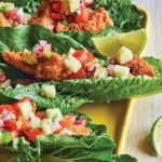 Four low-carb fish tacos--almond-flour-coated cod and cucumber salsa in lettuce leaves--with a slice of lime. You're gonna love these babies!