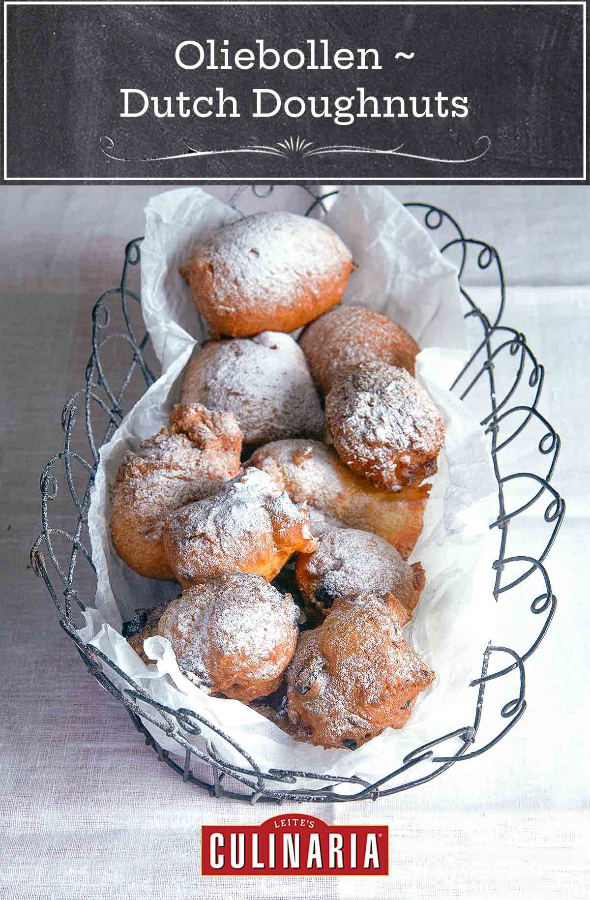 Oliebollen, or Dutch doughnuts, in a wire basket, covered with powdered sugar on a white tablecloth.