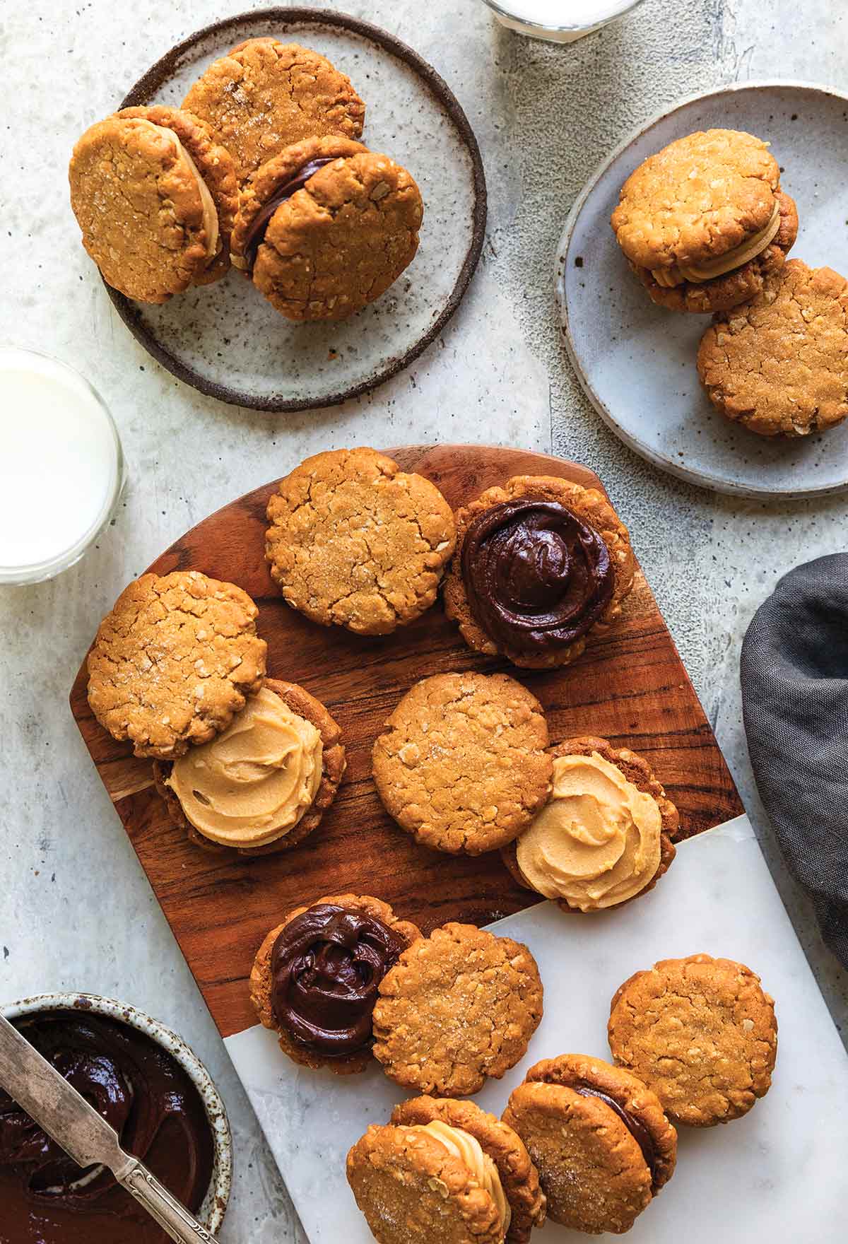 A cutting board covered with peanut butter-oatmeal sandwich cookies, some opened revealing their chocolate filling