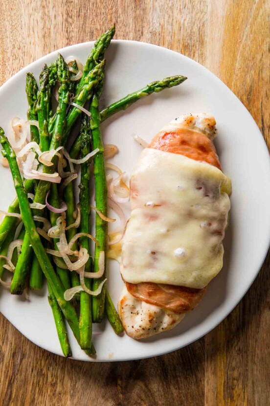 A white plate with prosciutto-wrapped chicken with asparagus on the site