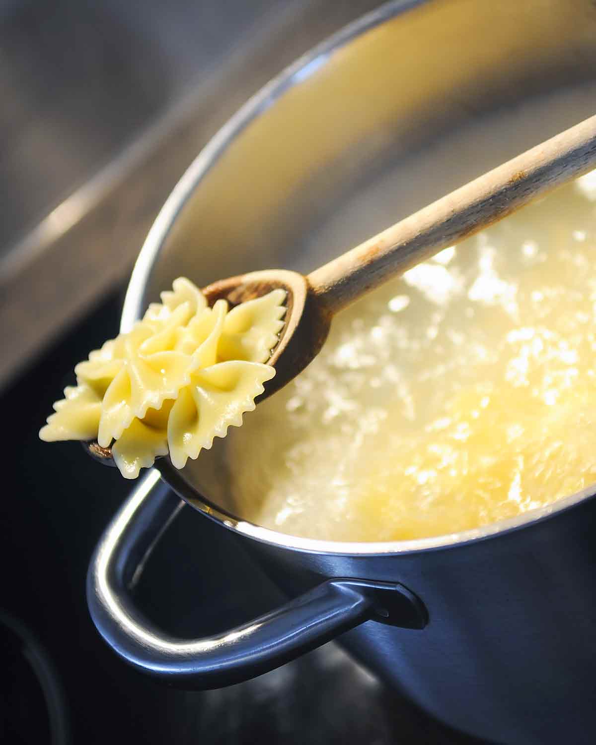 A pot of bowtie pasta that is still undercooked on the stove