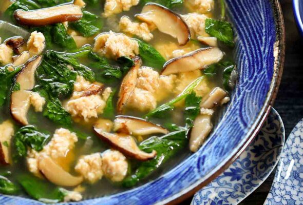 A blue and white bowl filled with velvet chicken and spinach soup