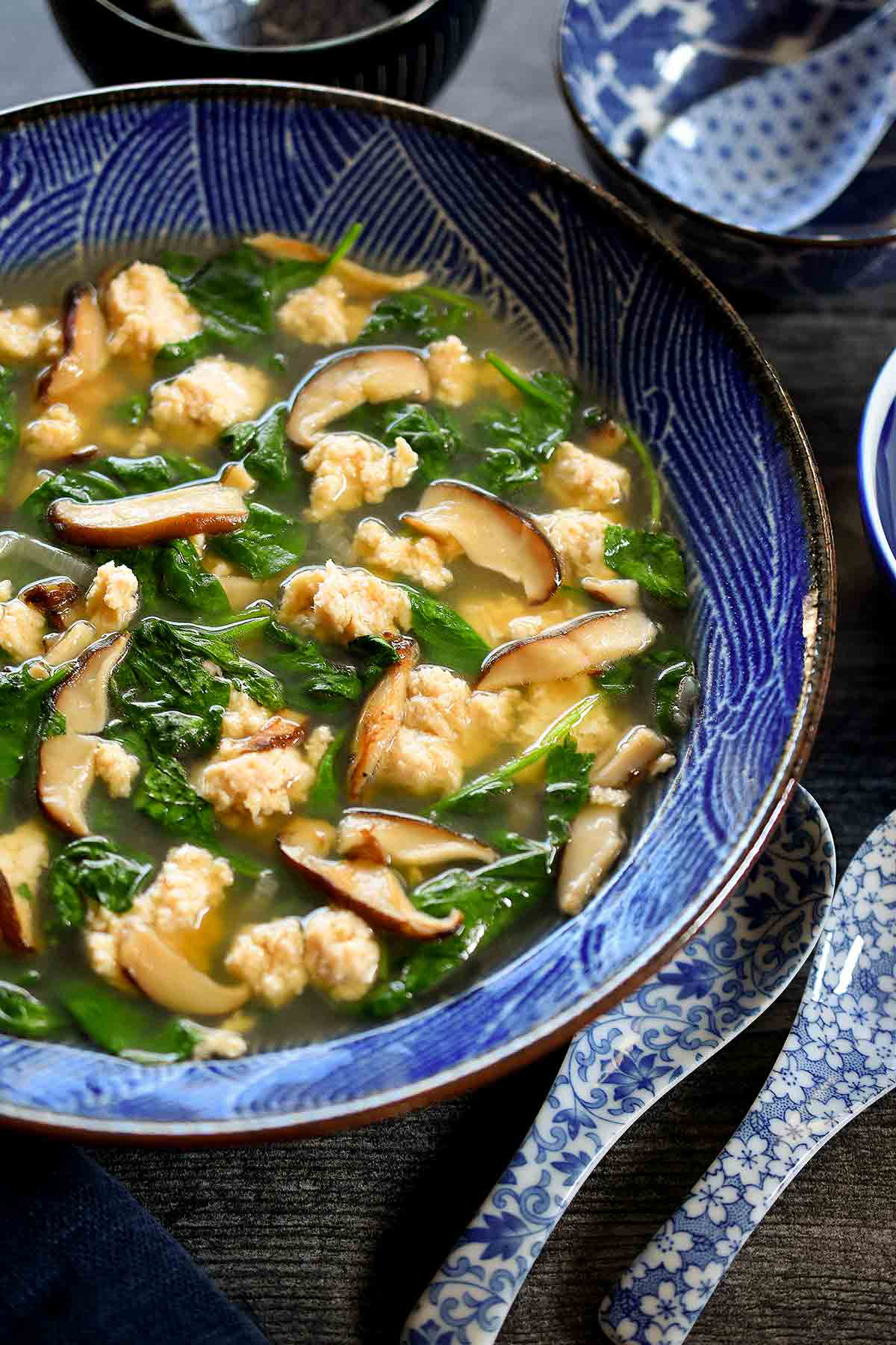 A blue and white bowl filled with velvet chicken and spinach soup