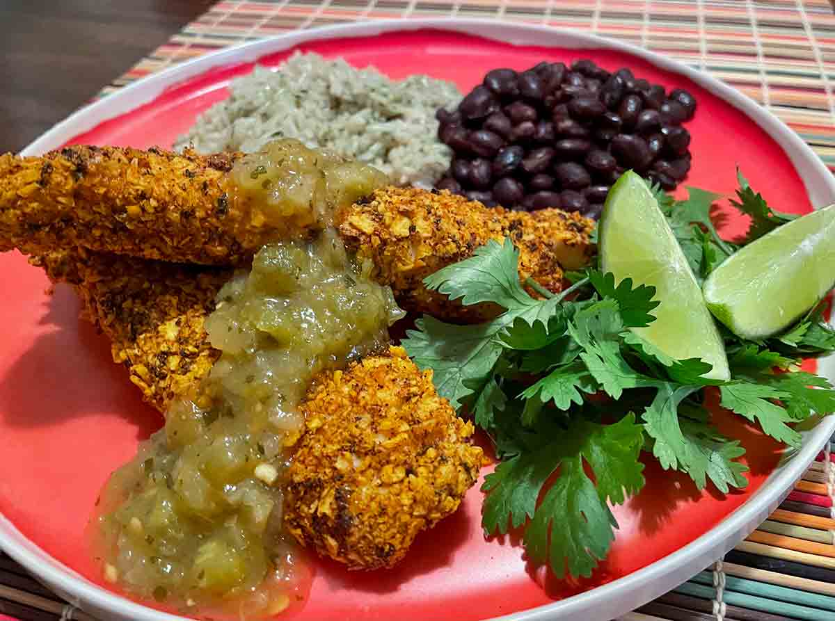 Air fryer tilapia with tortilla crust on a plate with rice and beans